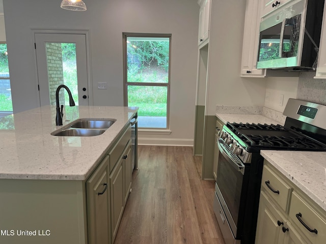 kitchen with appliances with stainless steel finishes, light stone countertops, sink, and an island with sink