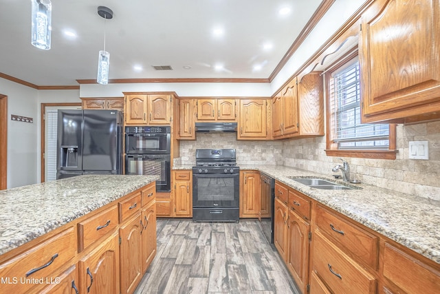 kitchen featuring sink, hanging light fixtures, tasteful backsplash, black appliances, and light wood-type flooring