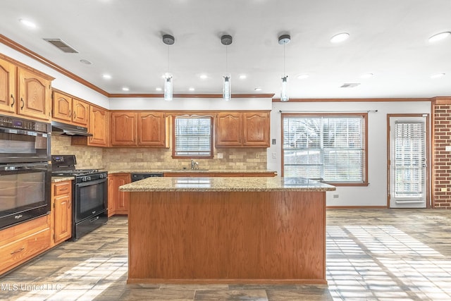 kitchen with a kitchen island, black appliances, decorative light fixtures, and light wood-type flooring