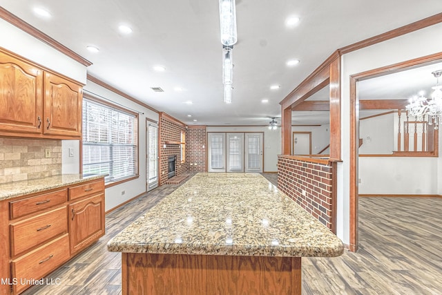 kitchen featuring pendant lighting, a center island, crown molding, ceiling fan, and light wood-type flooring