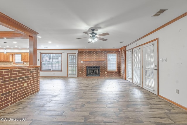 unfurnished living room with ceiling fan, ornamental molding, and brick wall