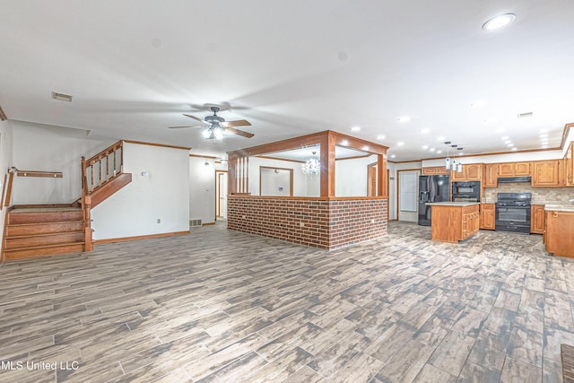 unfurnished living room featuring crown molding, ceiling fan, hardwood / wood-style floors, and brick wall