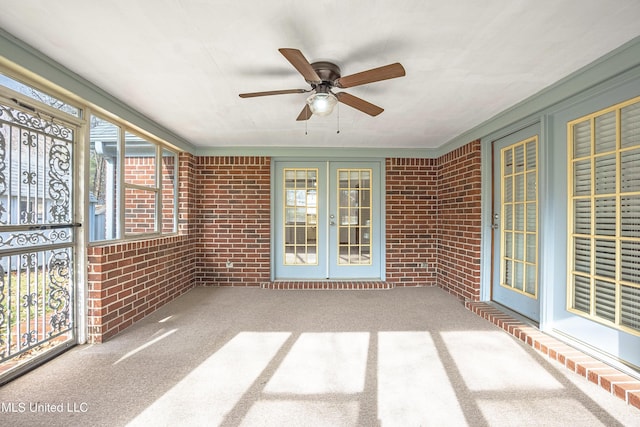 unfurnished sunroom featuring ceiling fan and french doors