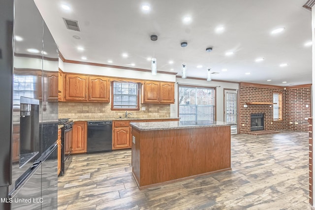 kitchen featuring sink, pendant lighting, decorative backsplash, a kitchen island, and black appliances