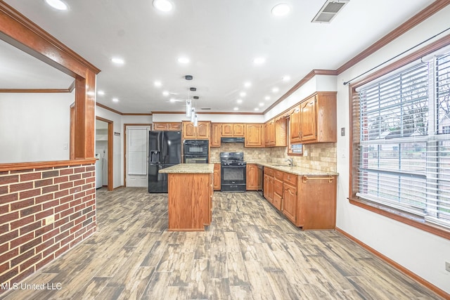 kitchen featuring crown molding, wood-type flooring, decorative backsplash, a kitchen island, and black appliances