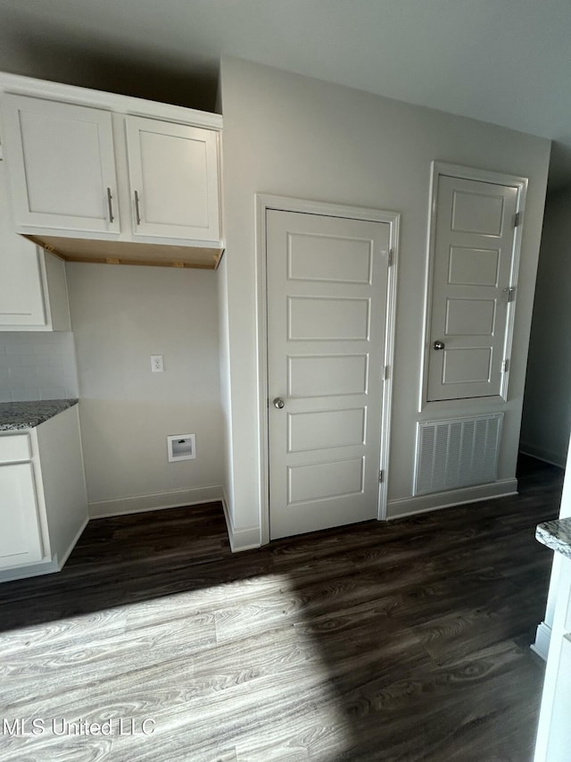 interior space with dark hardwood / wood-style floors, white cabinets, and stone countertops