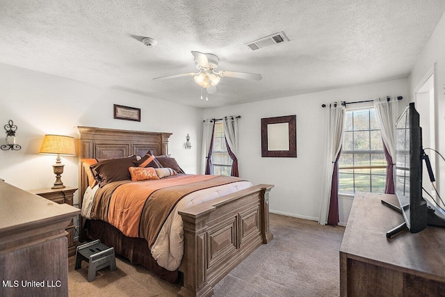 carpeted bedroom featuring ceiling fan and a textured ceiling