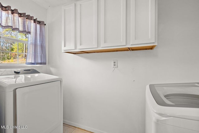 clothes washing area with independent washer and dryer, cabinets, and light tile patterned floors