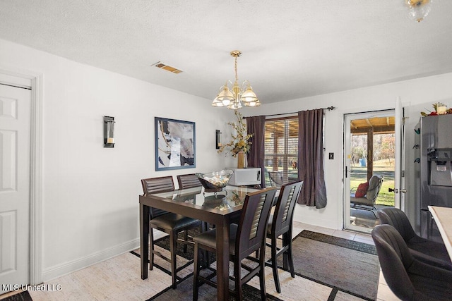 dining area with a notable chandelier, a textured ceiling, and light tile patterned flooring