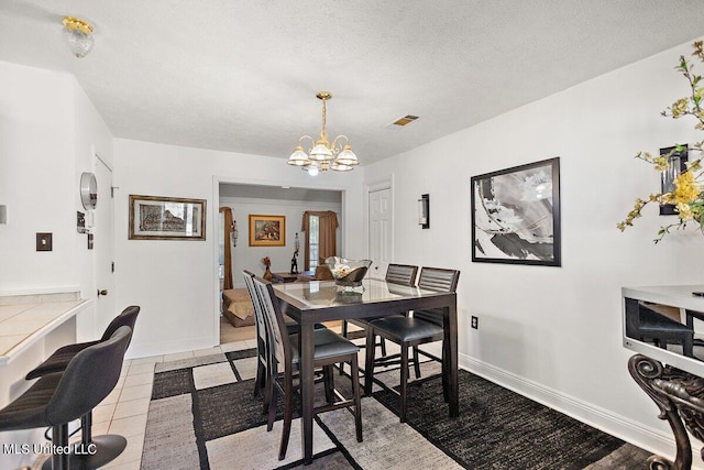 dining area with a chandelier, light tile patterned flooring, and a textured ceiling