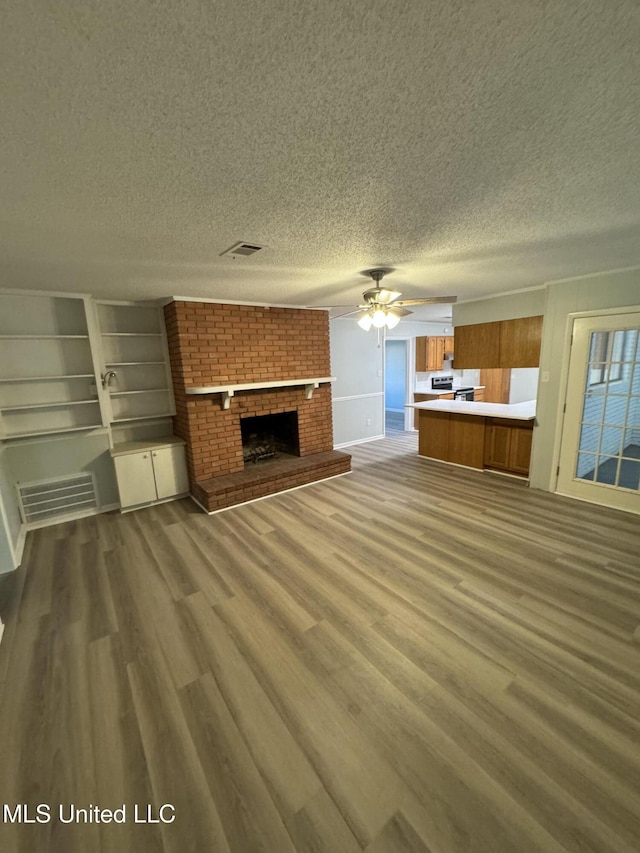 unfurnished living room featuring a fireplace, wood-type flooring, and a textured ceiling