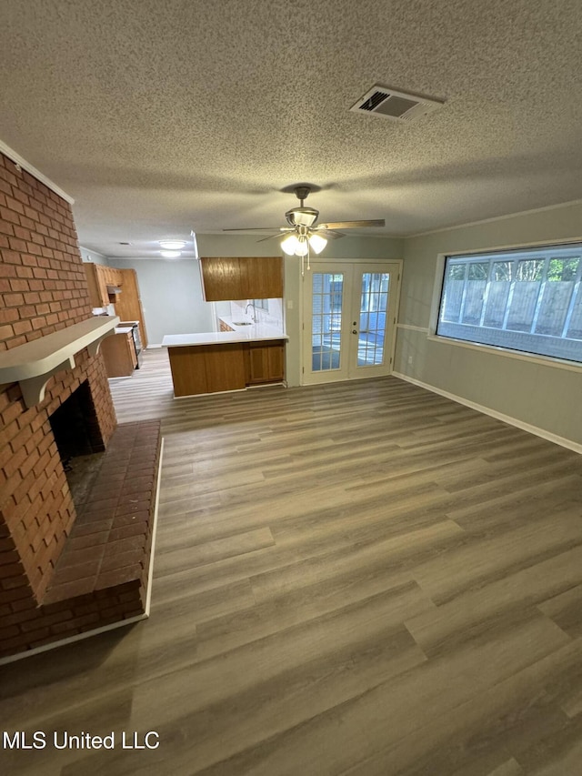 unfurnished living room with ceiling fan, hardwood / wood-style flooring, a fireplace, and a textured ceiling