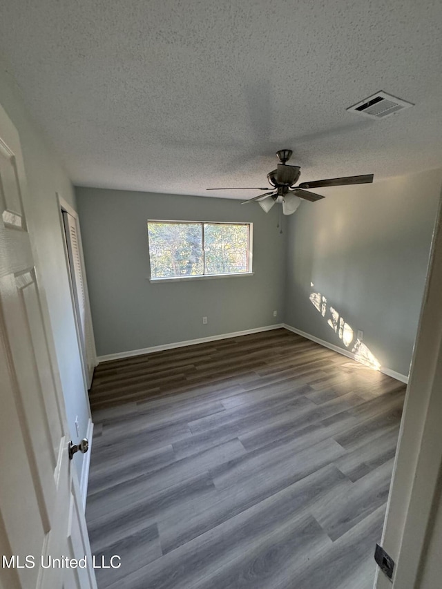 empty room with hardwood / wood-style flooring, ceiling fan, and a textured ceiling