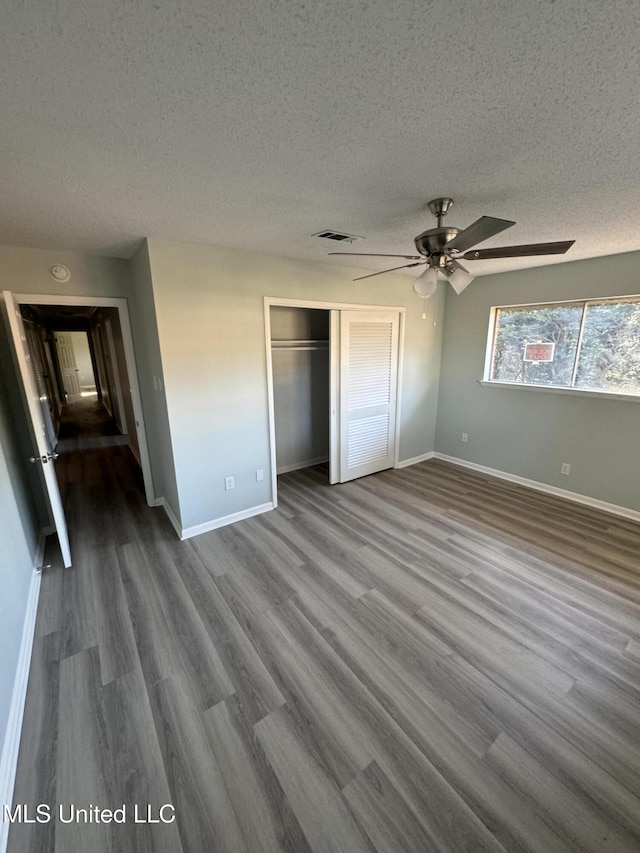 unfurnished bedroom with ceiling fan, wood-type flooring, a closet, and a textured ceiling