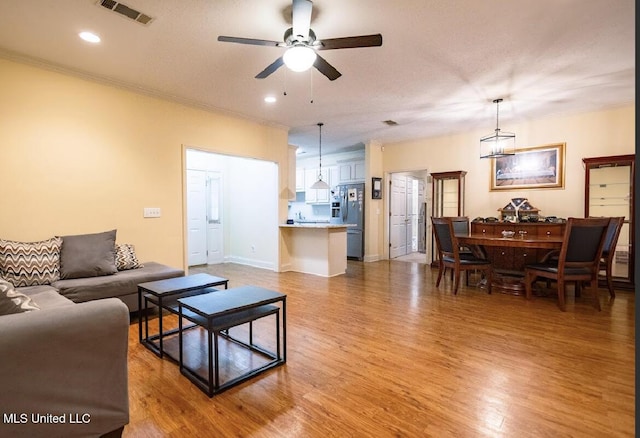 living room featuring crown molding, light hardwood / wood-style floors, and ceiling fan