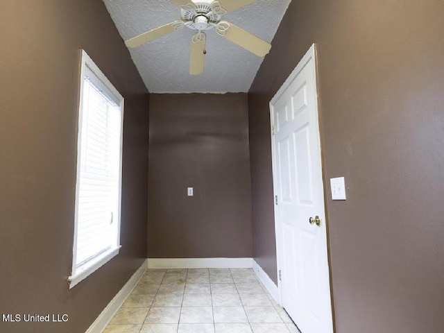 spare room featuring light tile patterned flooring, plenty of natural light, ceiling fan, and a textured ceiling