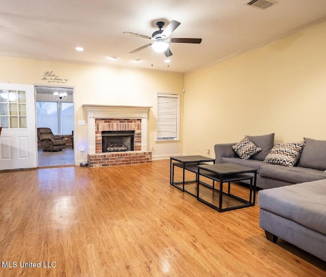 living room featuring crown molding, hardwood / wood-style flooring, a fireplace, and ceiling fan