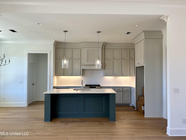 kitchen with decorative backsplash, hanging light fixtures, gray cabinets, light countertops, and a sink