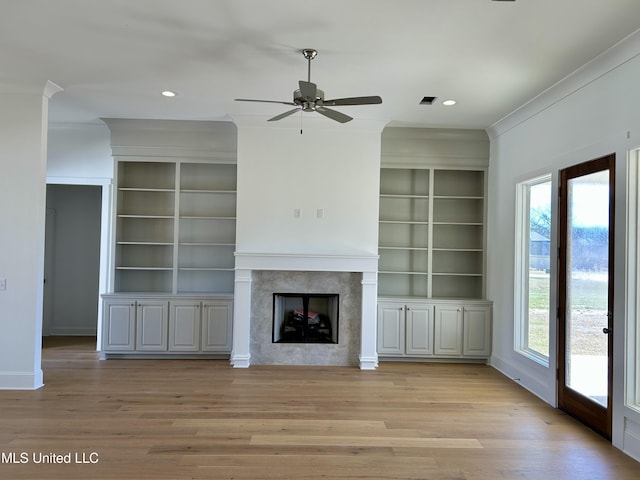 unfurnished living room featuring a wealth of natural light, a fireplace, and light wood-style flooring