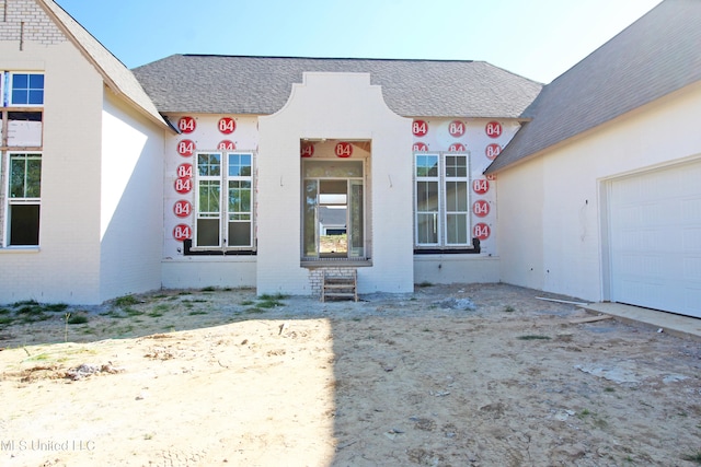 view of front of property featuring a garage, brick siding, and roof with shingles