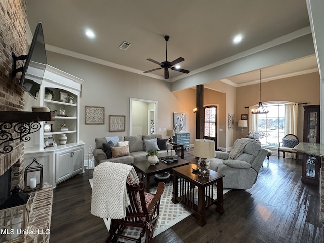 living room with built in features, ornamental molding, dark hardwood / wood-style flooring, a brick fireplace, and ceiling fan with notable chandelier