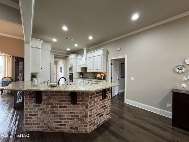 kitchen with a breakfast bar, white cabinetry, stainless steel appliances, custom exhaust hood, and kitchen peninsula