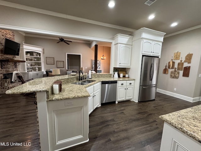 kitchen featuring sink, appliances with stainless steel finishes, light stone counters, white cabinets, and kitchen peninsula