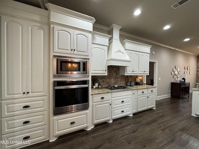 kitchen with white cabinetry, decorative backsplash, stainless steel appliances, and premium range hood