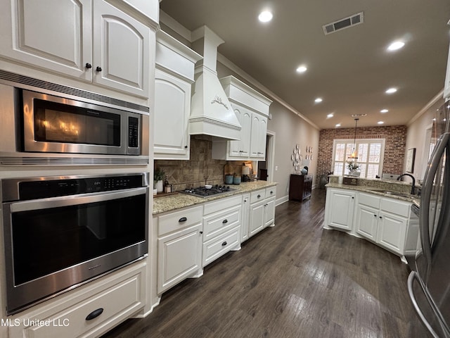 kitchen featuring sink, hanging light fixtures, stainless steel appliances, light stone countertops, and white cabinets