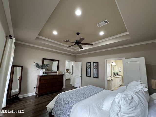 bedroom with ornamental molding, dark hardwood / wood-style floors, ensuite bath, and a tray ceiling