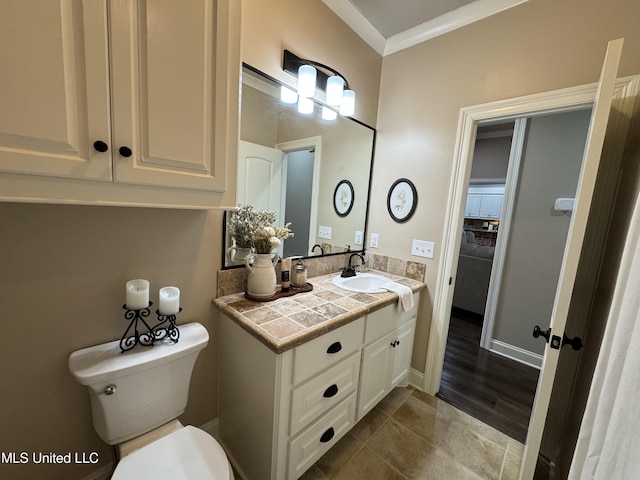 bathroom with ornamental molding, vanity, and toilet