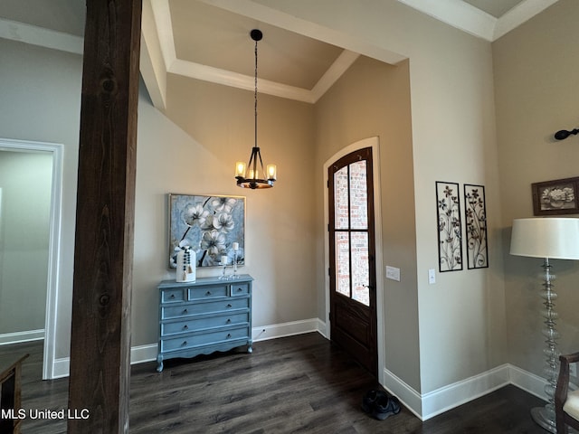 foyer entrance with crown molding, dark wood-type flooring, and a notable chandelier