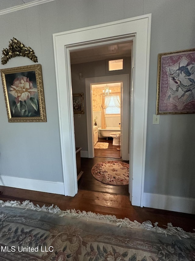 hall featuring a notable chandelier and dark wood-type flooring