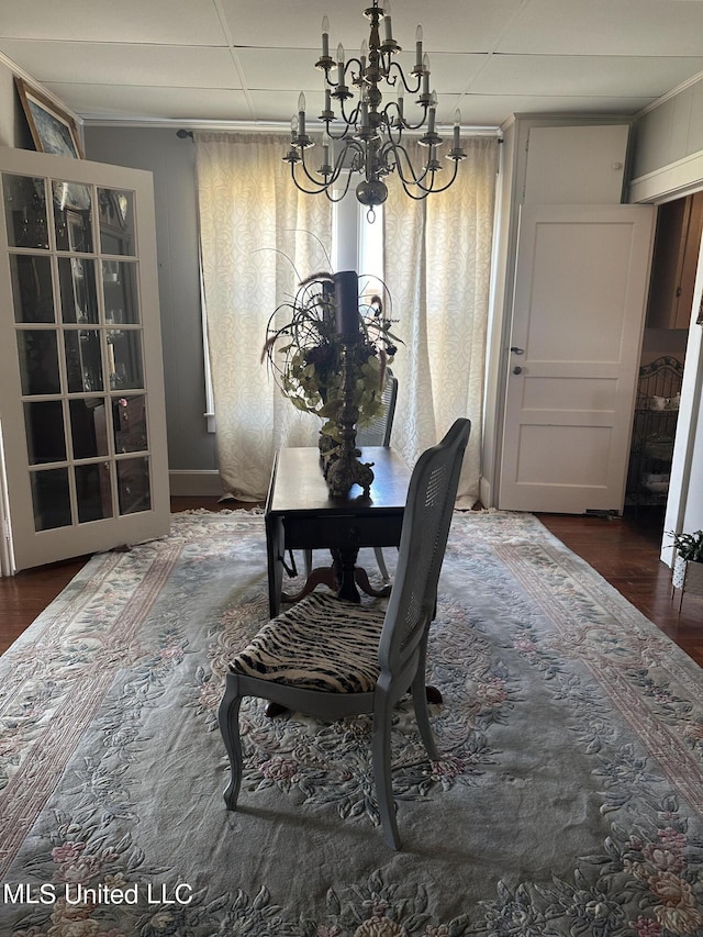 dining space with crown molding, dark hardwood / wood-style flooring, and an inviting chandelier