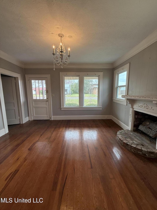 209 S Jackson St, Crystal Springs, MS 39059 - unfurnished living room with wood-type flooring, a fireplace with raised hearth, a notable chandelier, ornamental molding, and a textured ceiling