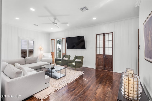 living room with dark hardwood / wood-style flooring, ceiling fan, ornamental molding, and wood walls