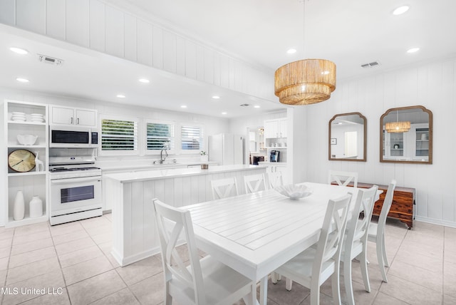 dining space with crown molding, sink, light tile patterned floors, and wooden walls