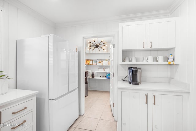 kitchen featuring white cabinets, crown molding, white fridge, and light tile patterned flooring