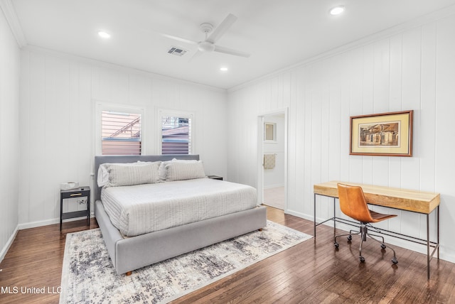 bedroom featuring connected bathroom, ceiling fan, dark hardwood / wood-style floors, crown molding, and wooden walls