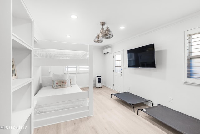 bedroom with light hardwood / wood-style flooring, a wall mounted AC, and crown molding