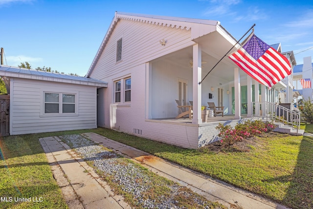 view of side of home featuring a porch and a lawn