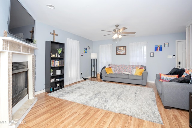 living room featuring a fireplace, light hardwood / wood-style flooring, and ceiling fan