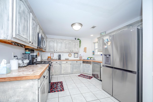 kitchen with tile counters, light tile patterned flooring, sink, and stainless steel appliances