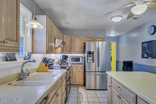 kitchen featuring appliances with stainless steel finishes, light brown cabinetry, sink, hanging light fixtures, and light tile patterned floors