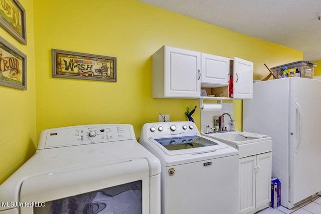 washroom with cabinets, light tile patterned floors, washer and clothes dryer, and sink