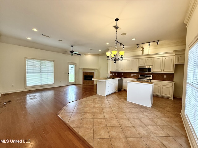 302 Bedford Ct, Brandon, MS 39047 - kitchen featuring stainless steel appliances, open floor plan, a fireplace, a chandelier, and a kitchen island