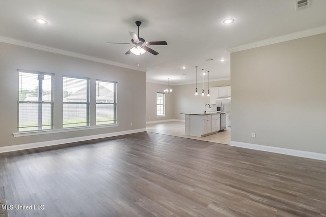 unfurnished living room featuring sink, wood-type flooring, ceiling fan with notable chandelier, and ornamental molding