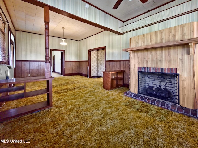 interior space featuring carpet floors, ceiling fan, a fireplace, and wood walls