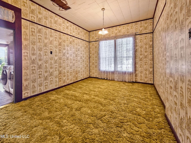 carpeted spare room with crown molding, plenty of natural light, wallpapered walls, and washer and clothes dryer