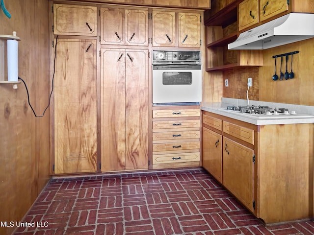 kitchen featuring open shelves, brick floor, white appliances, light countertops, and under cabinet range hood